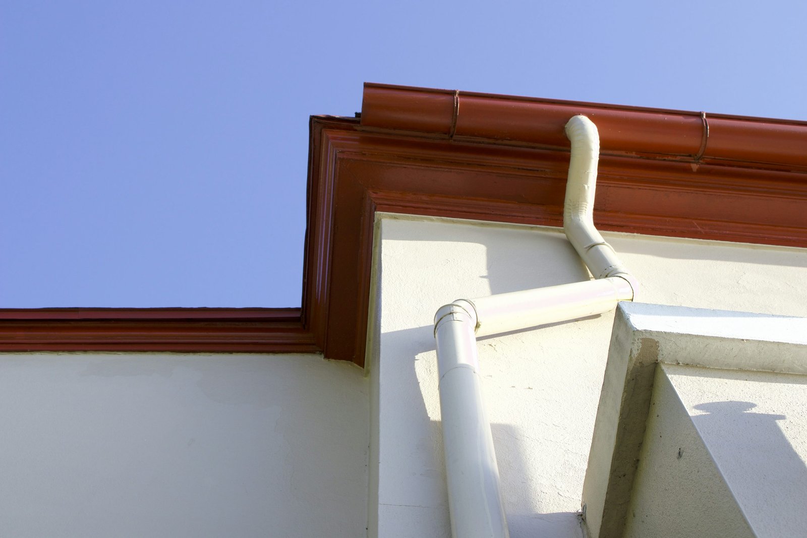 A gutter and downspout at a building roof edge